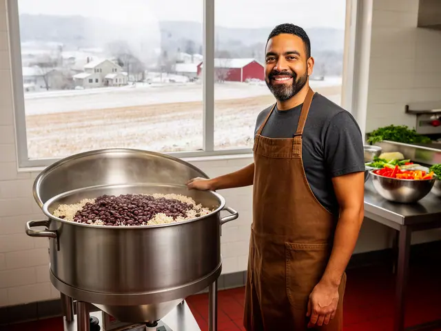 A smiling cook in a brown apron beside a new stainless-steel kettle of rice and beans in a tiled kitchen.